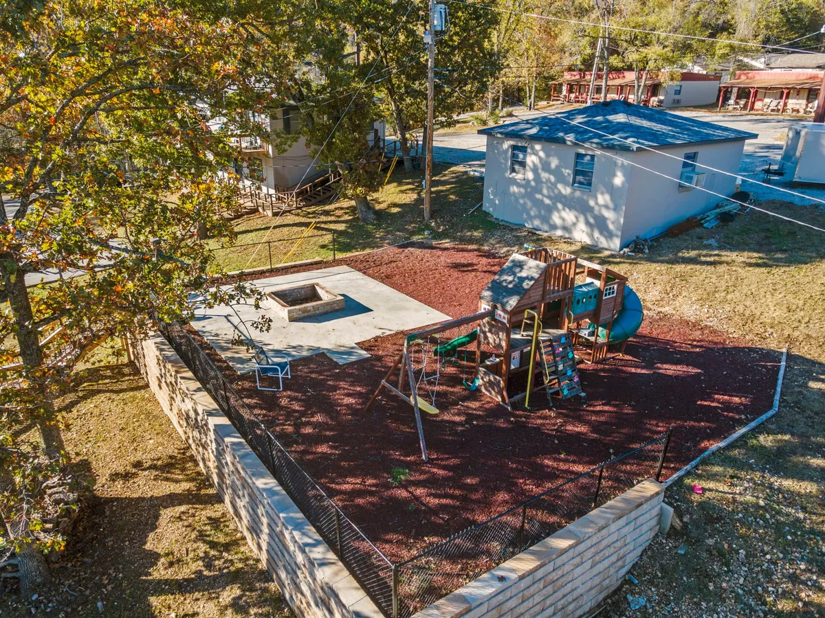 A cheerful, fenced playground with slides, a sandbox, and plenty of space for kids to play, all nestled among trees. The setting suggests a safe, fun environment for families with younger children to enjoy outdoor recreation beyond the lake.