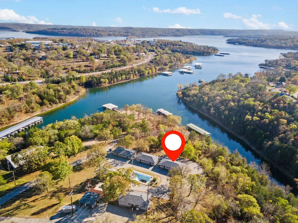 A sweeping exterior view of Table Rock Lake framed by lush greenery, with a cluster of lakeside buildings near the center. The image captures the peaceful shoreline and hints at various water-based activities and nearby amenities.