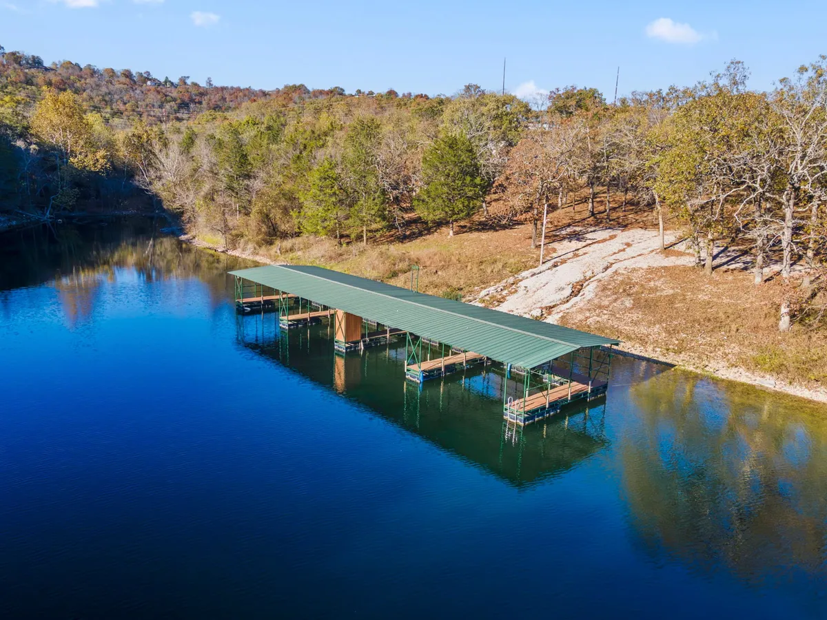 A serene lakeside dock stretches out over gentle water, framed by surrounding trees. The scene is peaceful and inviting, with the promise of lake views and tranquil moments just steps away from the patio.