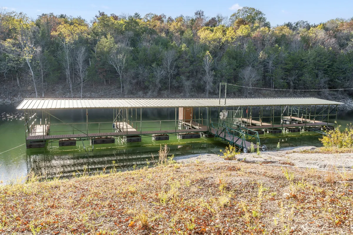 This image features a private dock extending into the calm waters of Table Rock Lake, surrounded by lush trees. The tranquil setting invites activities such as fishing, launching boats, or simply relaxing by the water's edge. The dock is clearly accessible and designed for easy enjoyment of the lake.